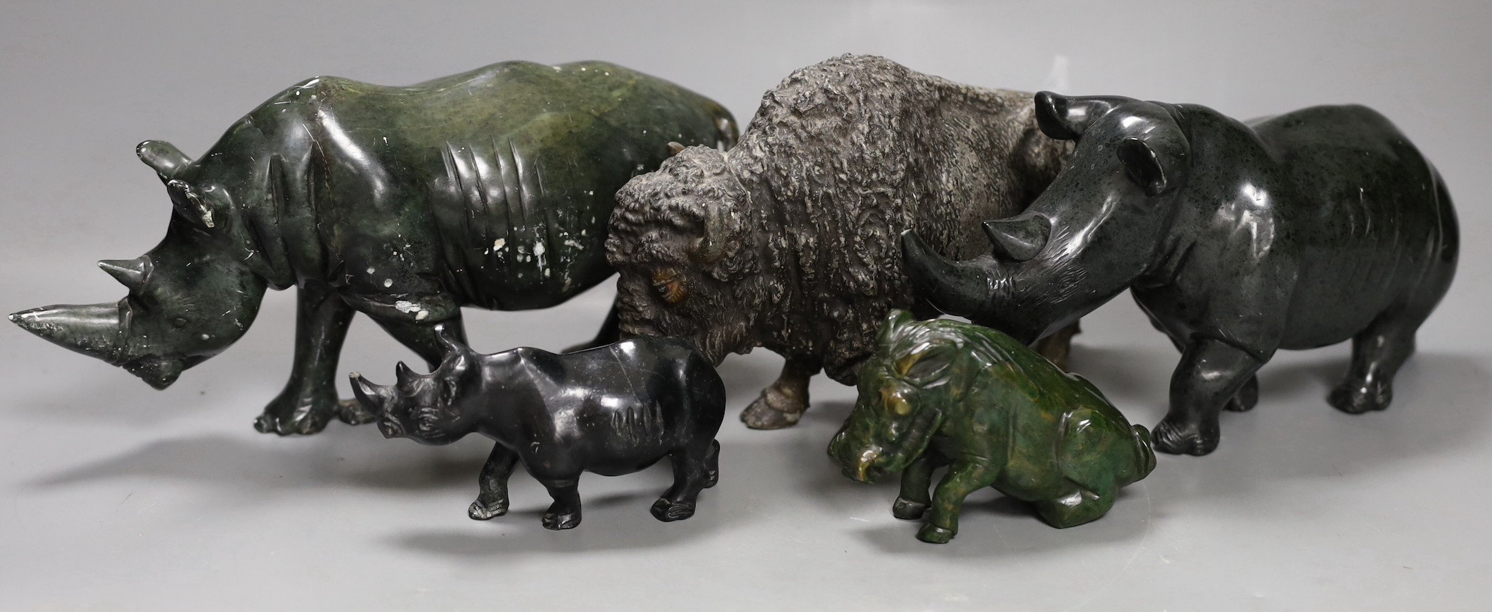 A selection of Zimbabwean animal carvings, to include, two carved Rhinos and two others and a spelter figure of a North American buffalo Tallest 14cm (5)